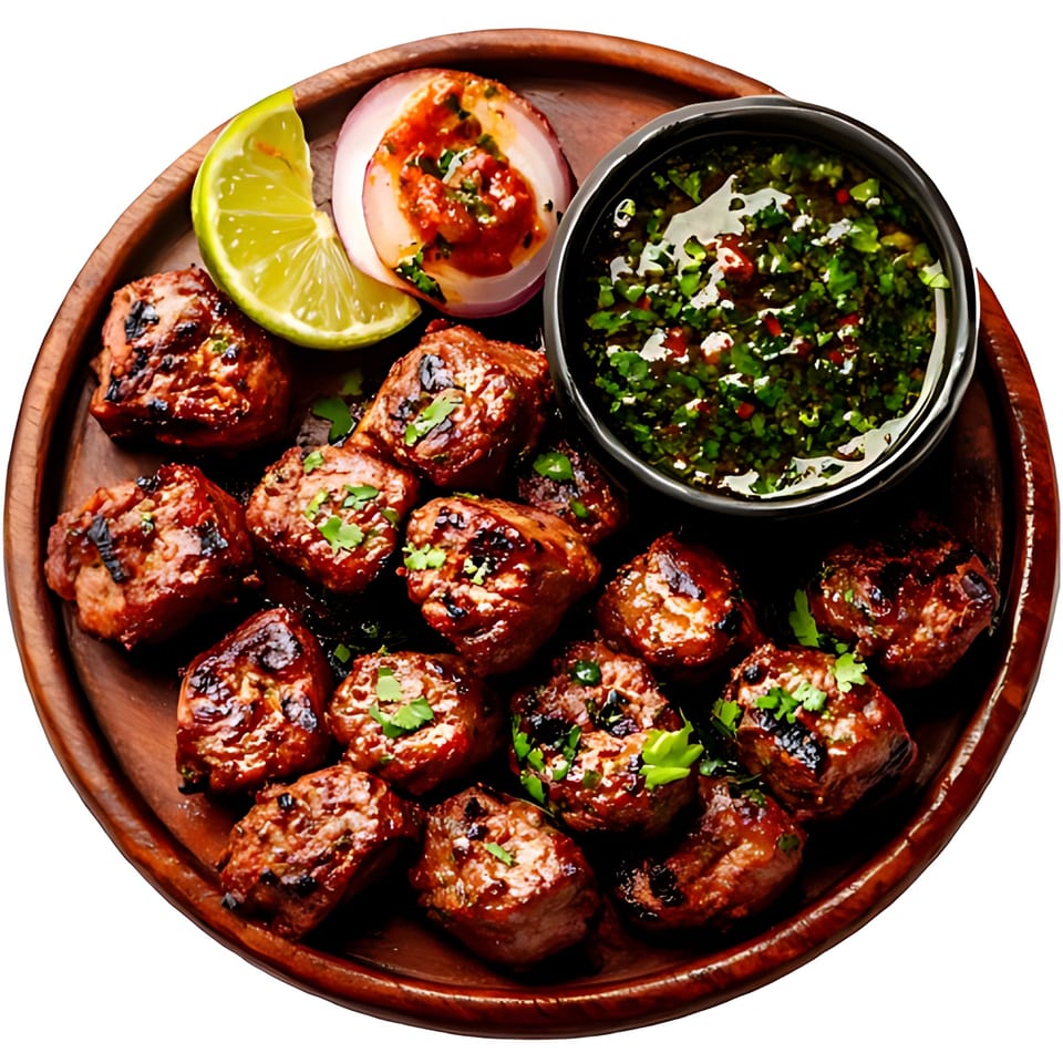 Afghan grilled meat skewers with lime, onion, and a green herb sauce on a wooden plate.